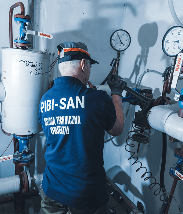 pracownik obsługi technicznej pracujący przy instalacji hydraulicznej